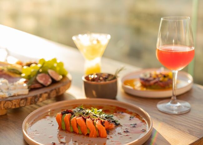 Plated gourmet dishes with wine and cocktails served at Osar Rooftop restaurant during sunset